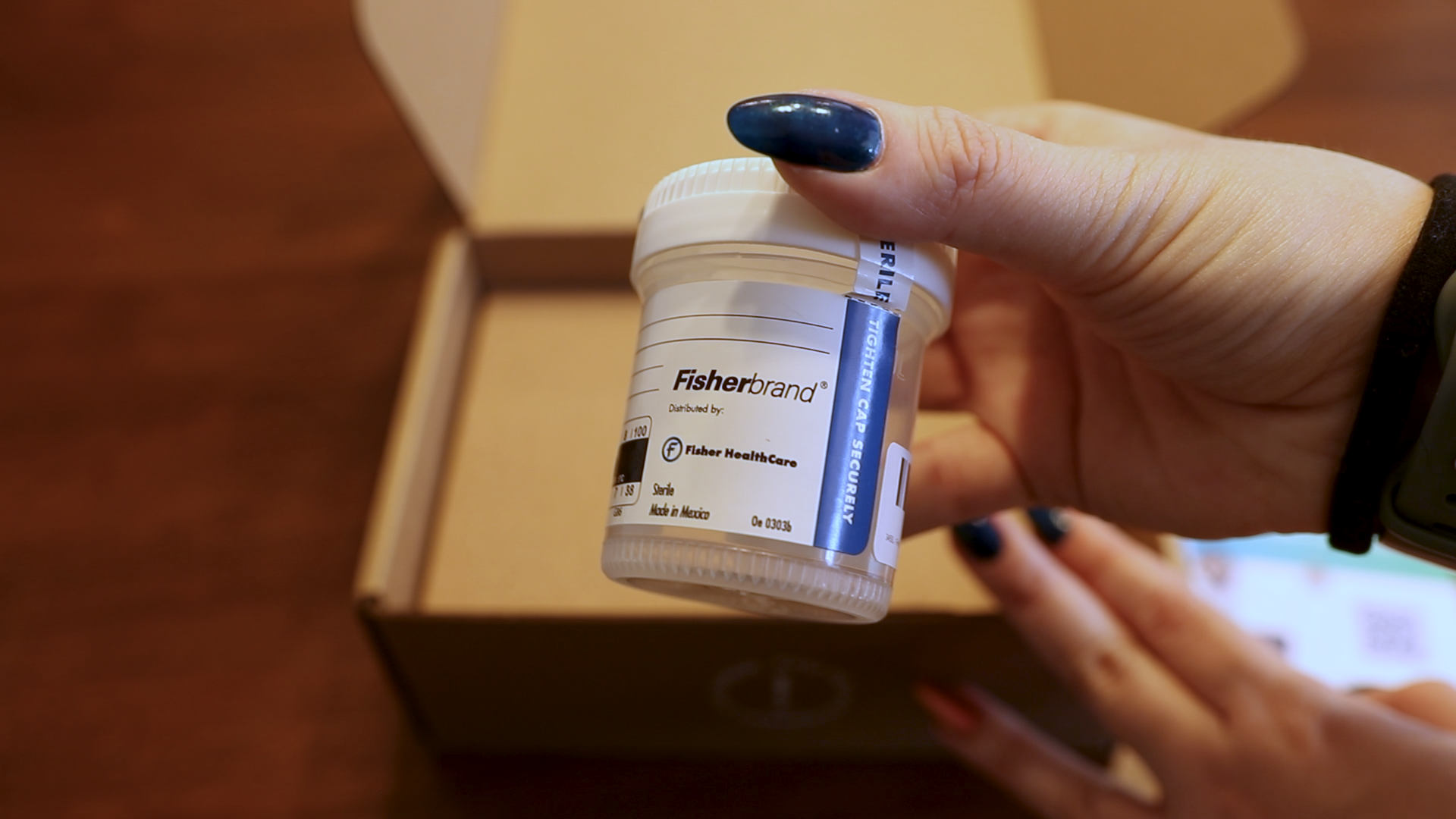 Woman's hand holding a Million Marker sample cup